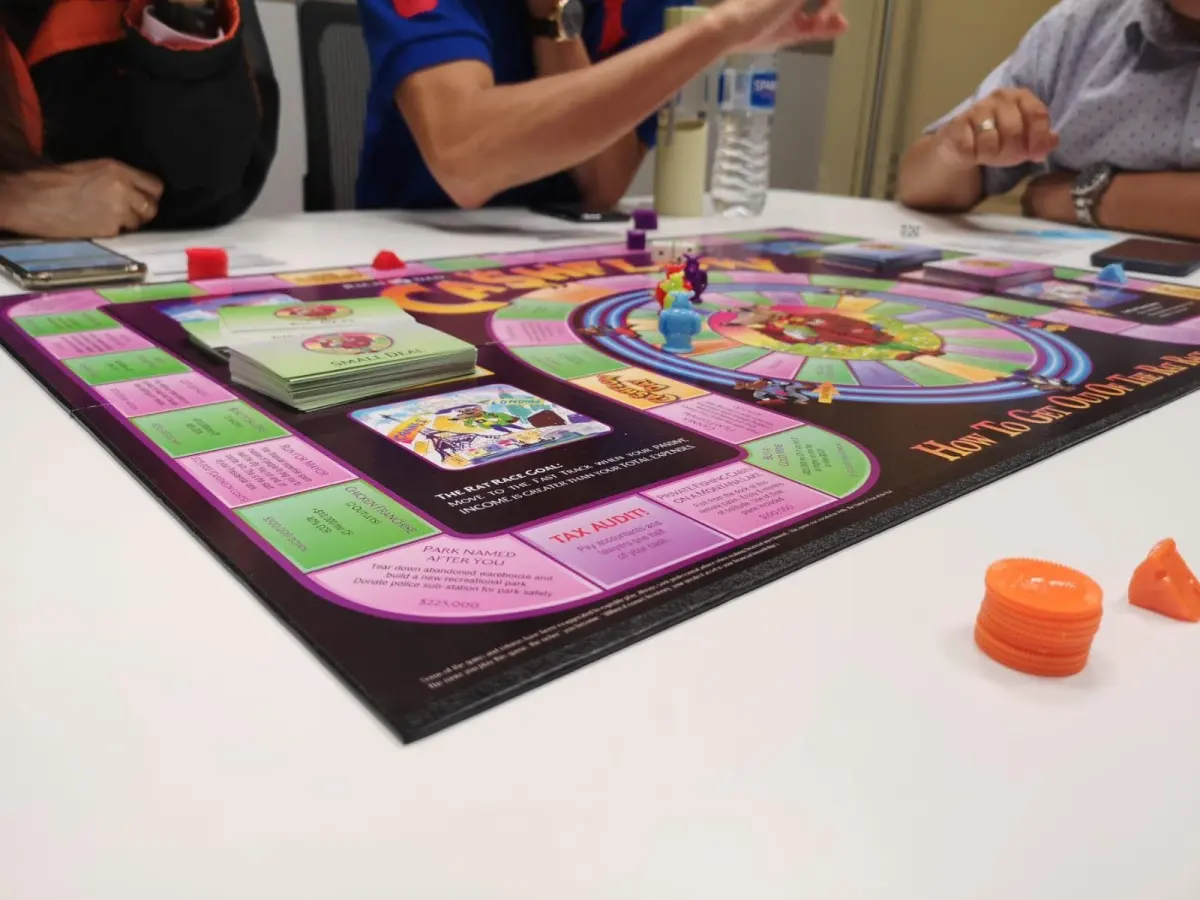 Players around a Cashflow board mid-game, with tokens and cards on the table.